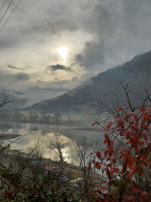 A serene landscape with a calm lake, mountains in the background, and a cloudy sky.
