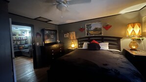 Een slaapkamer met een bed, een dressoir, een plafondventilator en twee bedlampjes.