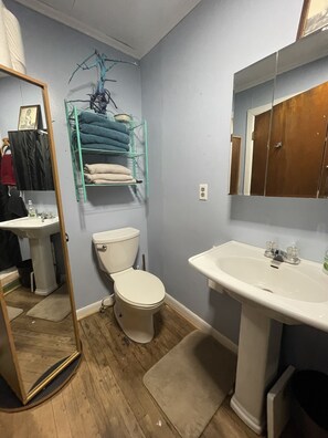 A bathroom with a white sink, a toilet, a mirror, and a towel rack.