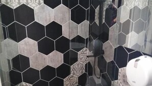 A bathroom with a toilet, a shower, and a hand dryer.