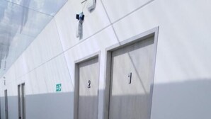 A corridor with numbered doors, a visible exit sign, and a ceiling with a light fixture.