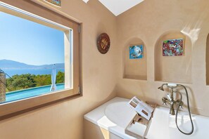 A bathroom with a bathtub, a window with a view of the sea, and two framed artworks on the wall. - Villa 6 bedrooms, pool, jacuzzi, sea view (PORTICCIO)