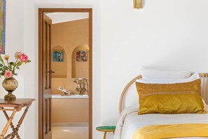 A bedroom with a bed, a bedside table with a vase of flowers, a wooden chair, and a bathroom visible through an open door. - Villa 6 bedrooms, pool, jacuzzi, sea view (PORTICCIO)