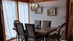 Un comedor con una mesa y sillas de madera, un candelabro y cuadros en la pared.