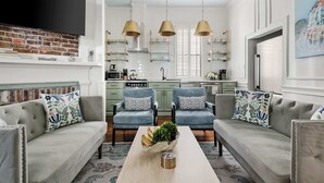 Ein modernes Wohnzimmer mit einer Sofagarnitur, einem Couchtisch und einem an einer Ziegelwand befestigten Fernseher.