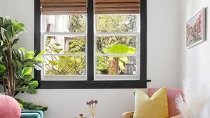 Un salón acogedor con un sofá color turquesa, un sofá rosa y una mesa de centro redonda con una vela.