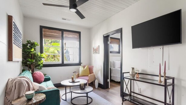 Una sala de estar moderna con un sofá color turquesa, una mesa de centro redonda y un televisor negro en la pared.