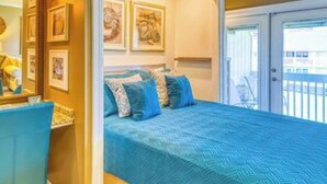A bedroom with a large bed, a dresser, and a door leading to a balcony. - Steps to the Beach! Water-Taxi to Destin Harbor! 5 Star Property! (Destin)