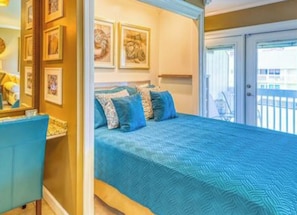 Un dormitorio con una cama grande, un aparador y una puerta que da a un balcón.
