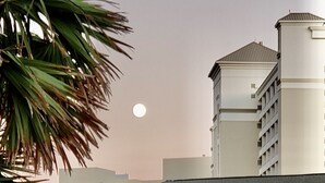 A multi-story building with a white facade, a balcony, and a staircase leading to the entrance. - Steps to the Beach! Water-Taxi to Destin Harbor! 5 Star Property! (Destin)