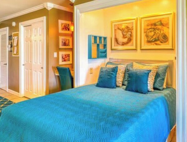 Un dormitorio con una cama grande, una puerta y una pared decorada con cuadros.