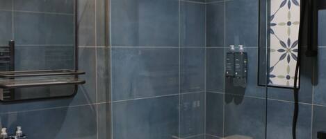 A modern bathroom with a glass shower enclosure, a white sink, and a mirror with built-in lights.