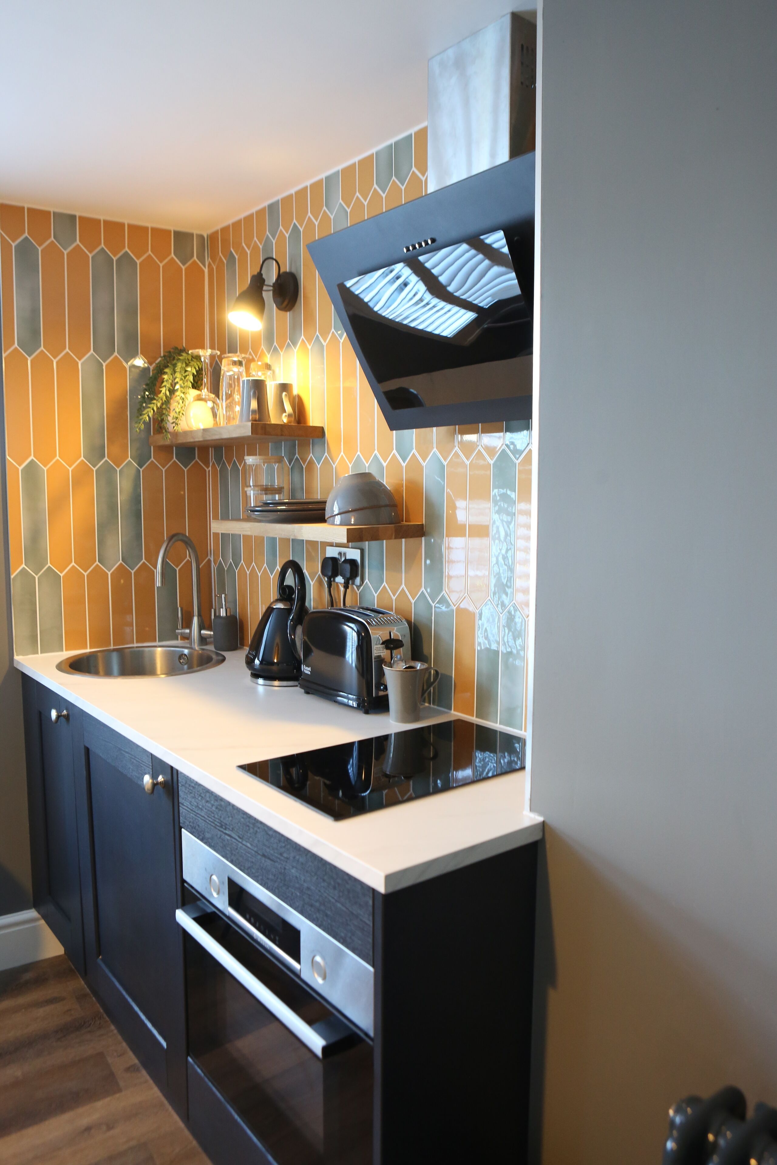 A modern kitchen with a white countertop, stainless steel appliances, and a backsplash with geometric patterns.