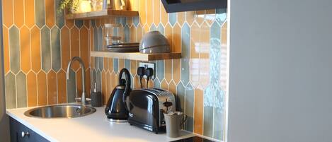 A modern kitchen with a white countertop, stainless steel appliances, and a backsplash with geometric patterns.