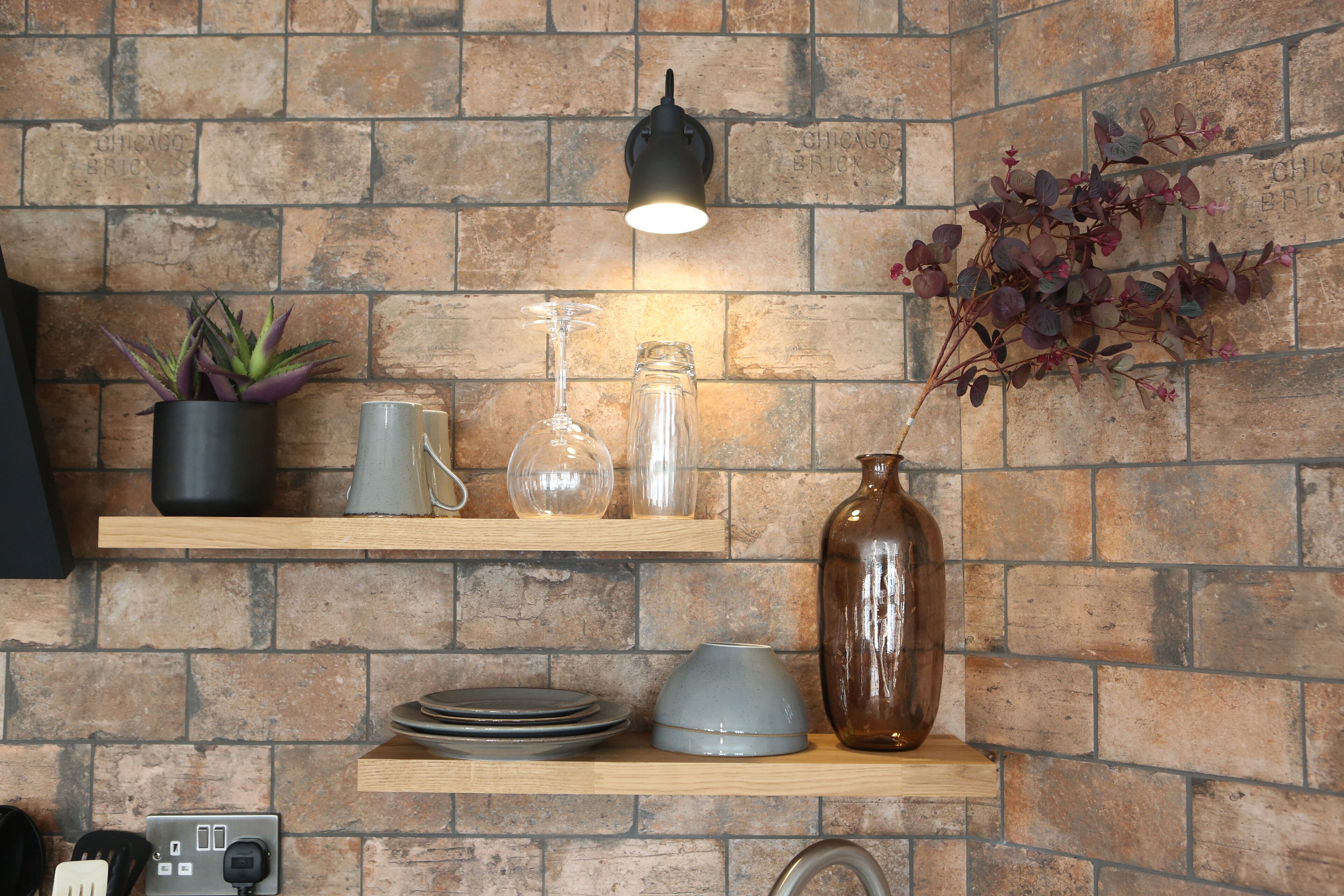 A kitchen with brick walls, wooden shelves, and various kitchenware.