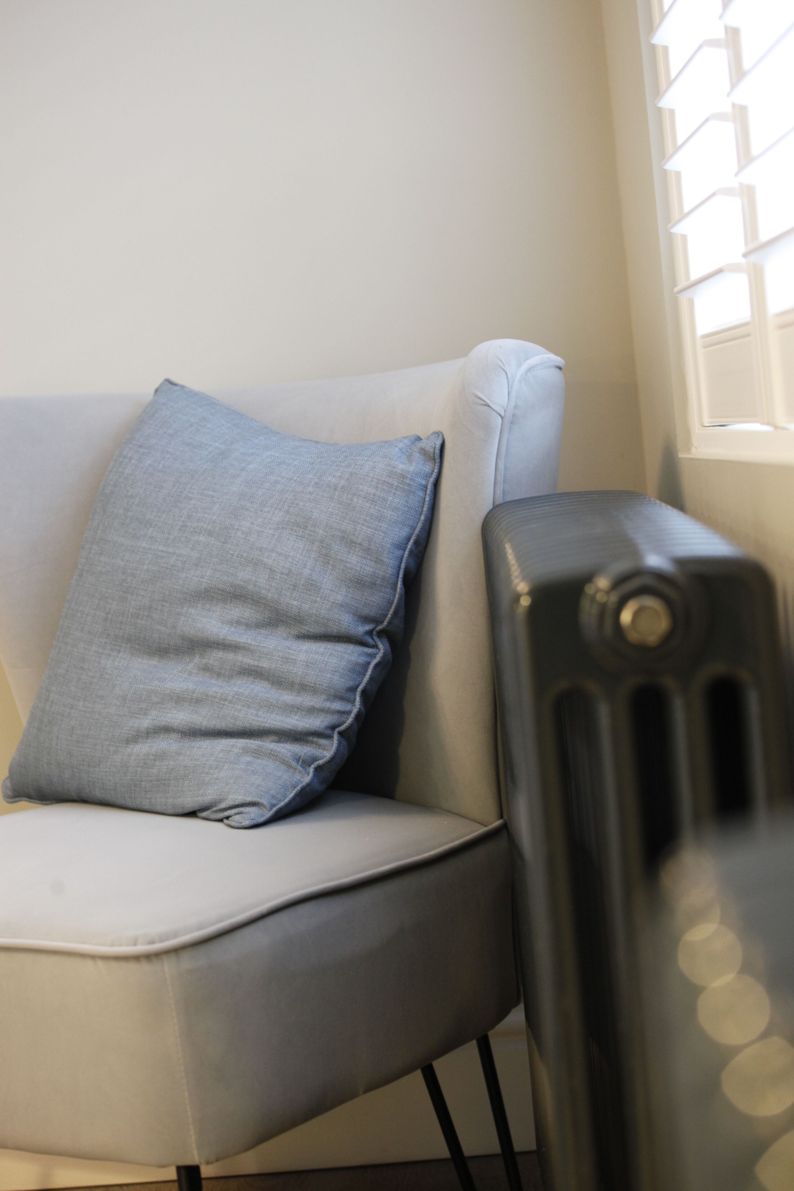 A modern living room with a grey sofa, a blue pillow, and a black radiator.