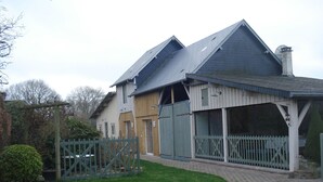 Une maison à deux étages avec un toit en pente, une allée bordée d’une clôture et un petit jardin.