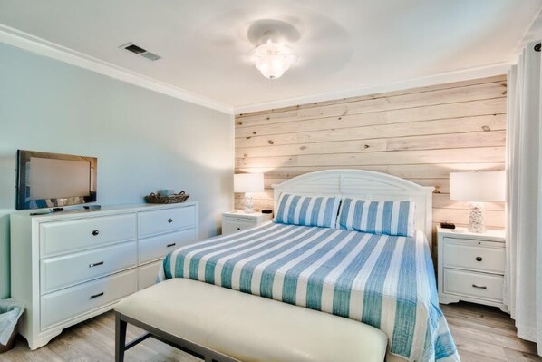 Une chambre à coucher avec un lit, des tables de chevet, un téléviseur et un panneau mural en bois.