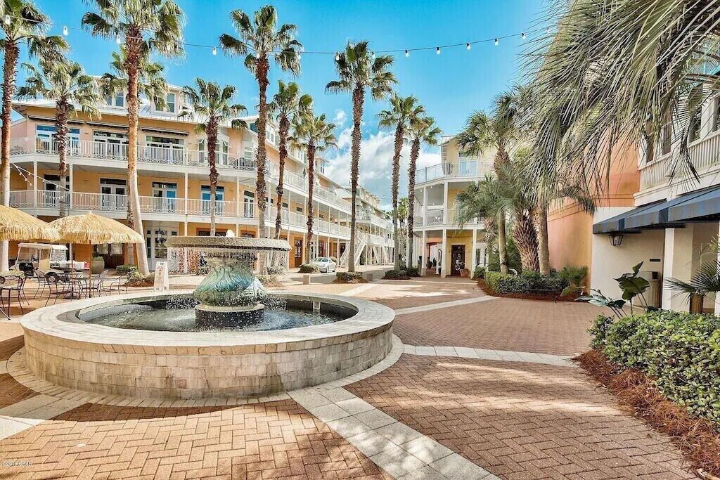 A hotel courtyard with a central fountain, palm trees, and outdoor seating areas.
