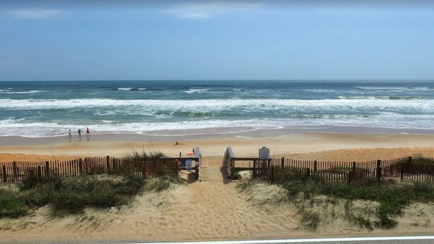A beach with a wooden fence, a lifeguard tower, and the ocean. - Remodeled Beach Oasis (Ormond Beach)