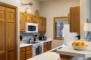 Una cocina con armarios de madera, microondas, estufa y ventana.