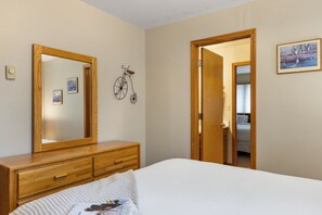 Un dormitorio con un espejo grande, un aparador de madera, una cama y una puerta que da a un baño.
