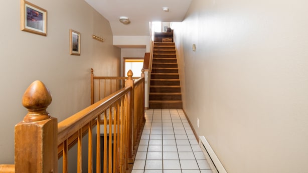 Un escalier avec des rampes en bois et un sol carrelé menant à un niveau supérieur.
