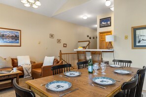 Un coin repas avec une table en bois dressée pour quatre personnes, entourée de chaises.