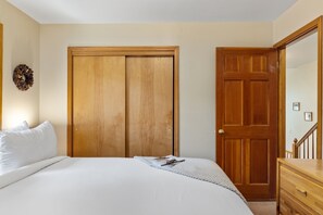 Une chambre à coucher avec un lit, une commode, une porte en bois et un miroir.