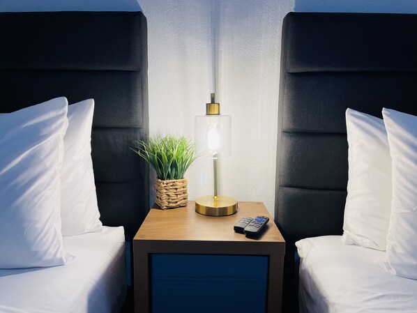 Relax in a stylish room with a single bed, flanked by two headboards, and a nightstand with a lamp and plants.