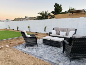 Relax in style on this serene patio, featuring a comfortable sofa and armchairs with white cushions.
