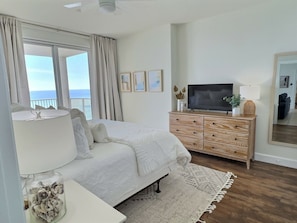 Ein Schlafzimmer mit Bett, Fernseher, Kommode und Meerblick.