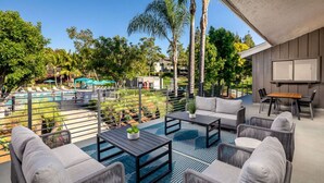 A rooftop patio with outdoor seating, a pool, and a view of the surrounding greenery. - Huge Oceanside 2BR Apartment|King & 2 Queen beds (Oceanside)