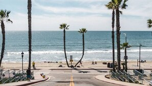 A beach with palm trees, a clear sky, and the ocean. - Huge Oceanside 2BR Apartment|King & 2 Queen beds (Oceanside)