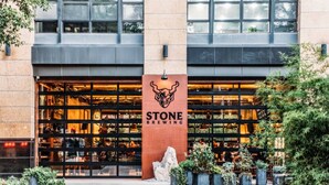 A building with a large sign reading "STONE BREWING" and a glass storefront. - Huge Oceanside 2BR Apartment|King & 2 Queen beds (Oceanside)