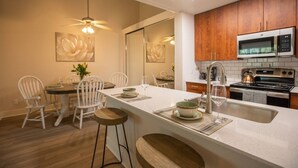 A modern kitchen with wooden cabinets, a stainless steel microwave, and a built-in oven. - Huge Oceanside 2BR Apartment|King & 2 Queen beds (Oceanside)