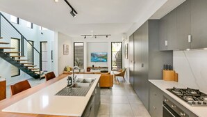 Una cocina moderna con una isla central, electrodomésticos de acero inoxidable y un comedor con una mesa larga.