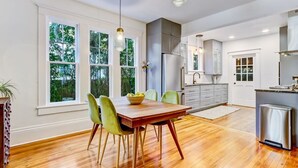 A modern kitchen with a wooden dining table, green chairs, and a stainless steel refrigerator. - Uptown Charmer|1mile walk to DT|2miles Vilano BCH (Saint Augustine)