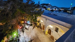 A nighttime view of a town with stone buildings, a prominent tower, and a street illuminated by street lamps. - Armesos Cave Hotel (Ürgüp)