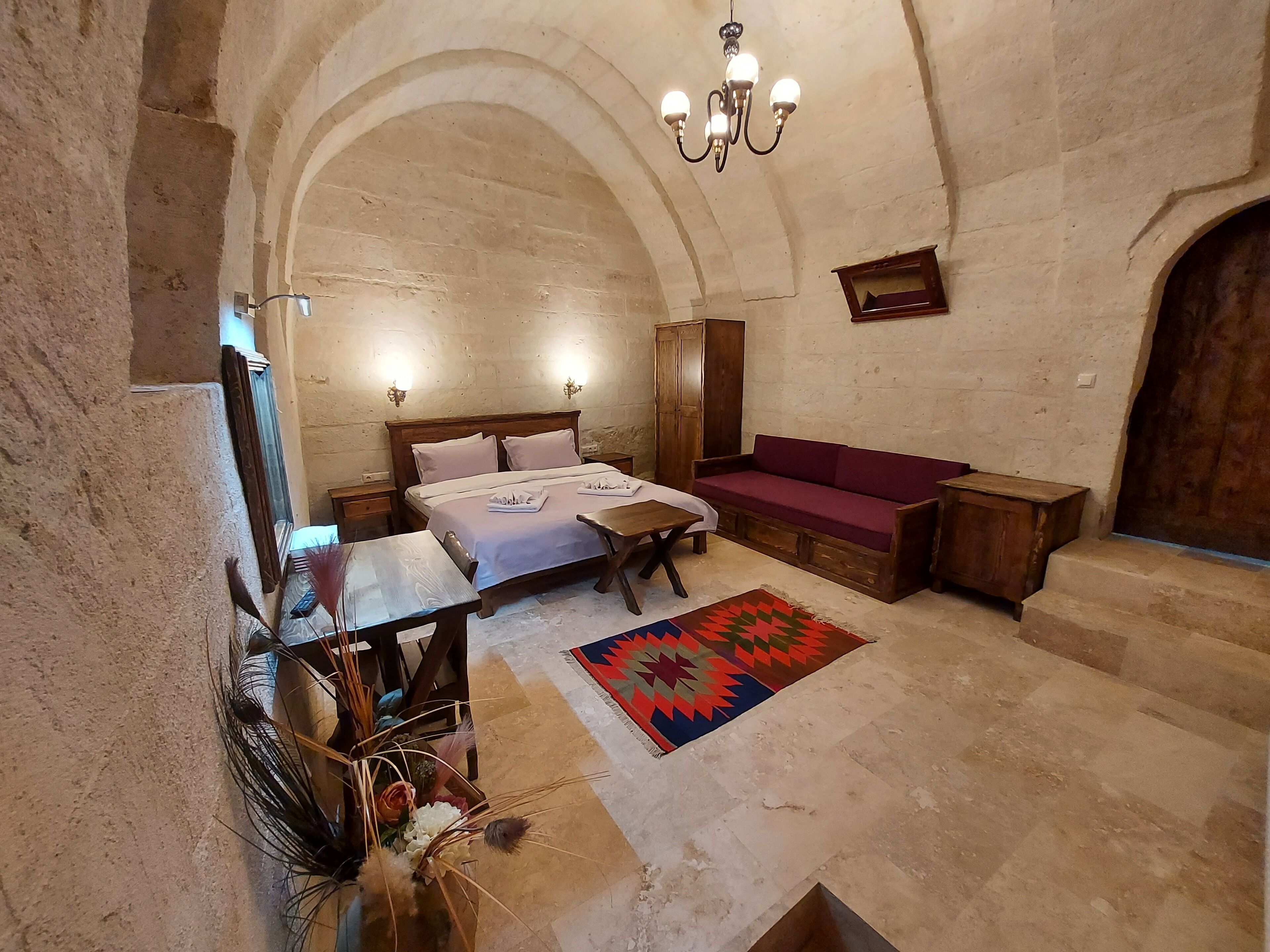 Una habitación con una cama, un banco de madera, una mesa y un candelabro.
