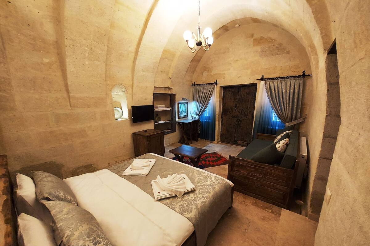A cozy room with a bed, a sofa, a small table, and a television.