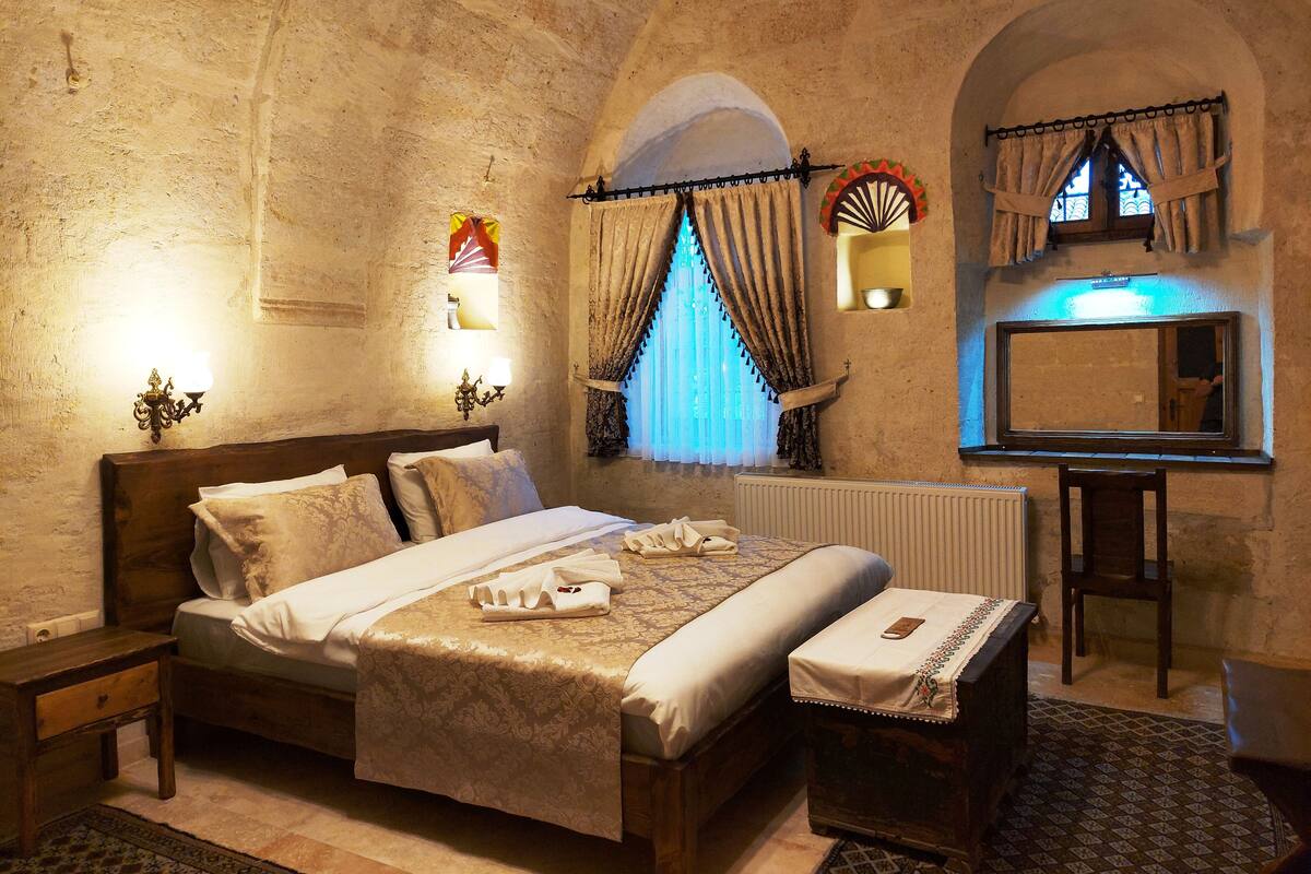 A traditional room with a bed, bedside table, and a small stool.