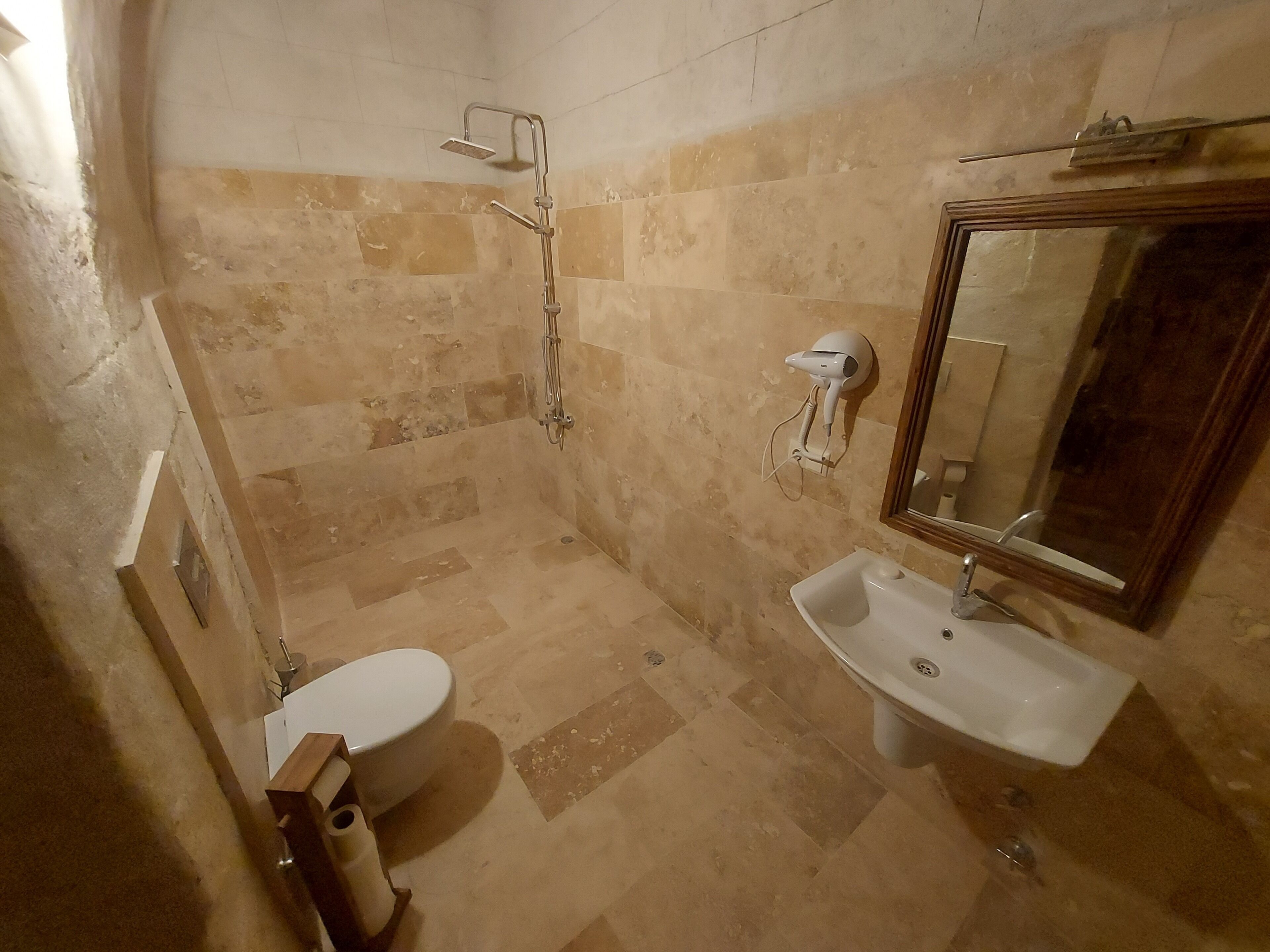 Un baño con inodoro, lavamanos, ducha y espejo.