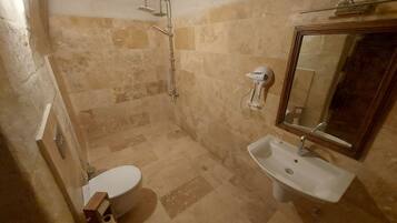 Un baño con inodoro, lavamanos, ducha y espejo.