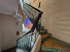 A spiral staircase with ornate metal railings and patterned floor tiles.
