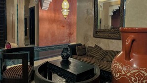 A traditional interior with a sofa, a coffee table, a decorative vase, and a hanging lamp.