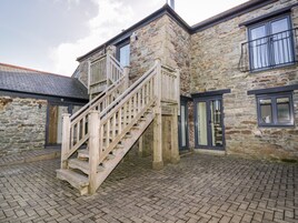 A stone building with a wooden staircase leading to a balcony.