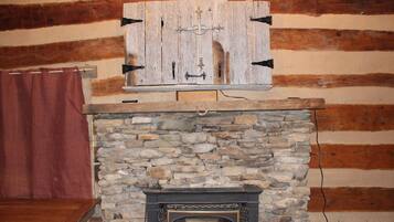 Een stenen openhaard met een houten plank en een ruwe houten wand.