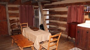 A rustic wooden room with a table, chairs, a wooden bench, and a cabinet. - Step back in time a charming 1880 historic cabin (Jonesborough)