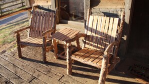 Two rustic wooden chairs on a wooden deck outside a building with a wooden door and window. - Step back in time a charming 1880 historic cabin (Jonesborough)
